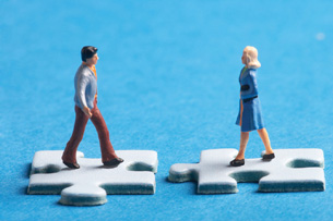 Toy figures stand on different puzzle pieces.