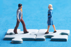 Toy figures stand on joined puzzle pieces.