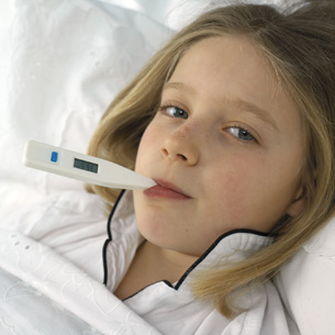 The photo shows a young girl getting her temperature taken with a thermometer.