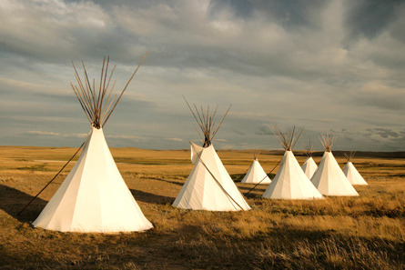 The photo shows a group of tipis.