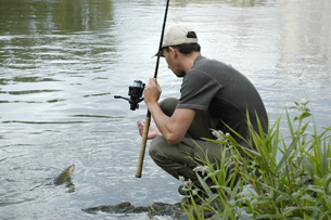 The photo shows a fisherman with his fishing rod catching a fish.