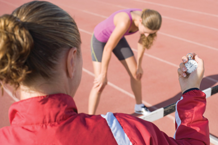 It is a photo of a track athlete catching her breath and her coach with a stopwatch.