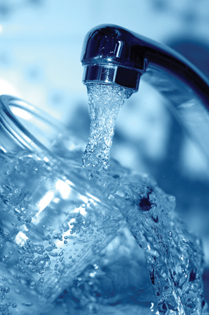 A photograph of a drinking glass being filled with water from a kitchen tap.