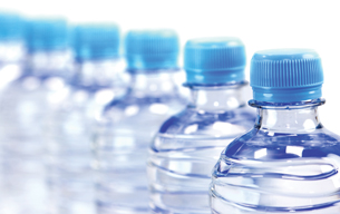 A photograph of many plastic bottles containing water. The bottles are aligned in a row.