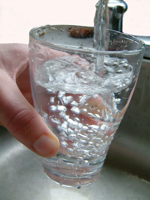 A photograph shows a drinking glass being filled with water from a kitchen tap.
