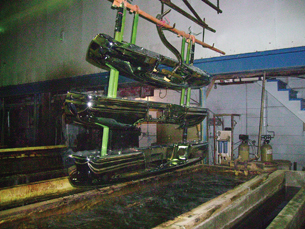 A photograph shows a commercial electroplating operation. Three car bumpers are held in a rack above a vat containing nickel ions.