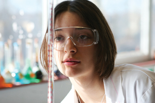A photograph shows a female student reading the level of a solution in a burette.