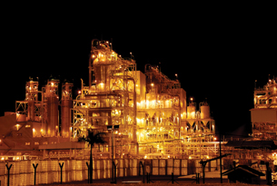 A photograph shows a brightly lit petrochemical plant at night.