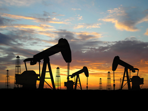A photograph shows several oil wells and pumpjacks against a night sky.