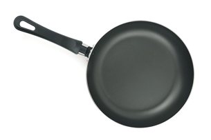 A photograph shows a black frying pan. The inside of the pan has a black coating.