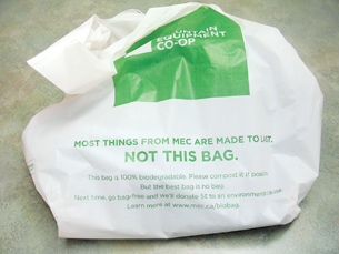 A photograph shows a plastic bag from the store, Mountain Equipment Co-op. Writing on the bag says “Most things from MEC are made to last. NOT THIS BAG. This bag is 100% biodegradable. Please compost it if possible.”