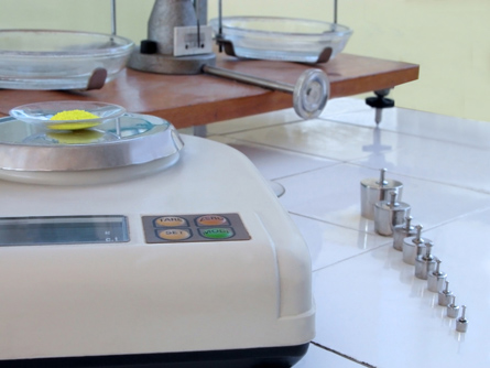 A photograph shows a variety of materials in a chemistry lab, including a pan balance and standard masses.