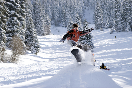 A photograph shows a snowboarder going over a jump.