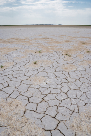 A photograph shows a large area of dry, cracked earth.