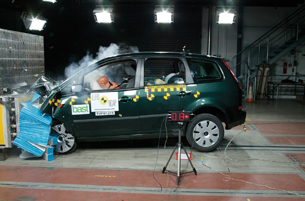 The photo shows a crash test dummy coming to a stop as a minivan crashes into a barrier. 