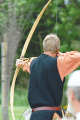 An archer is shown pulling back an arrow on a bow and aiming at a target.