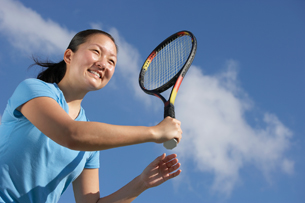 A young woman is shown striking a tennis ball with a tennis racquet. 