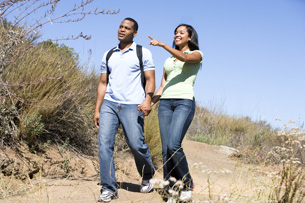 Couple walking on path holding hands and smiling.