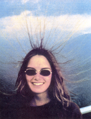 The image is a head and shoulders picture of a young woman standing at a lookout in Sequoia National Park, the mountain scenery visible in the background.  Her hair is standing on end.