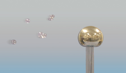 The photograph shows bubbles drifting toward the globe of a Van de Graaff generator.