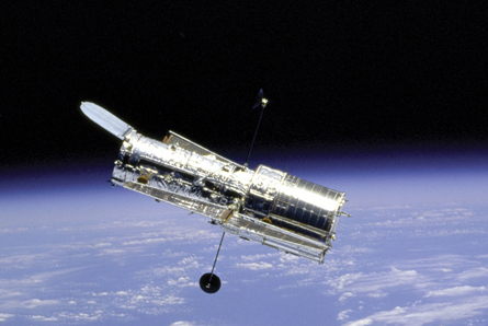 A photograph shot from space shows the Hubble Space Telescope orbiting Earth.