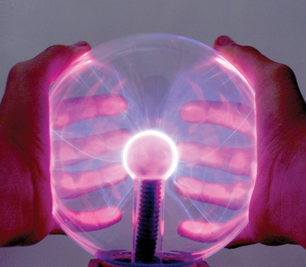A photo shows two hands wrapped around a plasma lamp. Blue and purple streamers are shown radiating from the central orb to the outside glass.