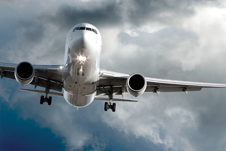 A jet airliner is about to land; there are dark clouds in the background.