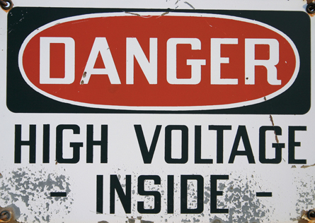 The photograph shows a warning sign that reads “Danger: High Voltage Inside.”