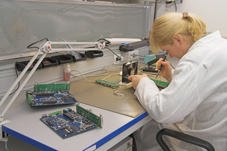 The photo shows a female technician working with an electric circuit. 