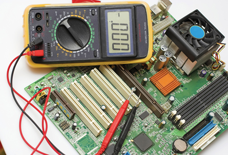 The photo shows a multimeter sitting on top of a computer circuit board. 