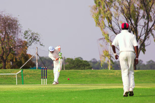 A photo shows two people playing cricket.