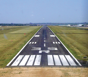 A photograph shows the end of an airplane runway marked with large numbers in white paint. The numbers must be changed periodically, as they are assigned relative to the Earth’s moving magnetic poles.