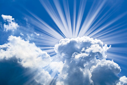 A photo shows a beautiful blue sky with sun rays coming out from behind clouds.