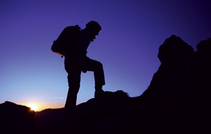 A photograph shows a hiker in silhouette climbing a mountain at dawn.