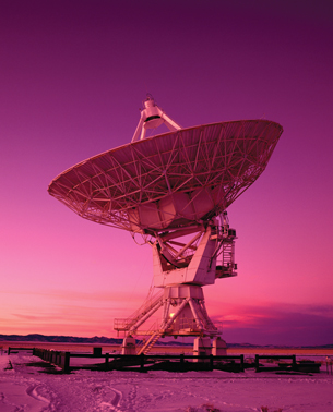 A photograph shows a very large communication satellite dish in a field.