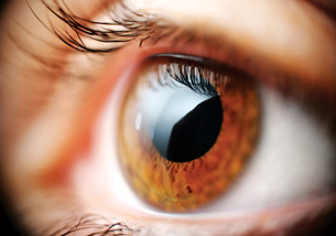 A photograph shows a close-up of a human eye. The lens in the eye refracts light to focus light on the back of the eye.