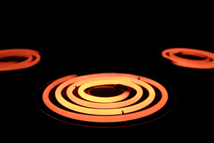 A photograph shows the glowing coils of three stove elements, with the focus on the centre element. Its yellow and red colours indicate that the temperature is greater near the centre and coolest on the outside of the coil.