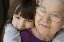 This photo shows a young girl hugging an elderly woman, possibly her grandmother.