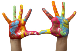 This photo shows a child’s hands completely covered in different colours of paint. It appears that the child’s hands have been painted.