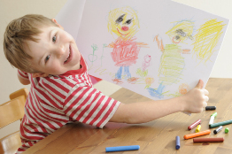 This photo shows a young boy with a drawing he has created.