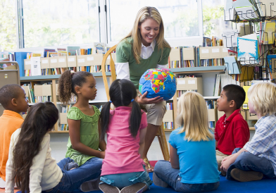 This photo shows an adult female with a group of young children of diverse ethnic backgrounds.