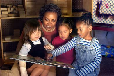 This photo shows a woman reading to three young girls.