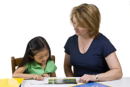In this photo a child and a child care worker read a book.