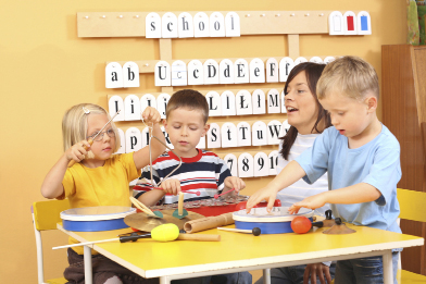 An activity with musical instruments is going ahead in this photo of three children and a child care provider.