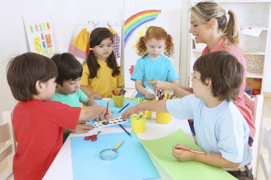Art activities are an important component of a child care facility. In this photo, five students and a child care provider work on an art project.