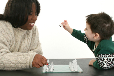 In this photo a caregiver is playing a board game with a child.