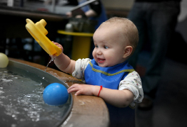 In this photo a young child plays with toys in the water.