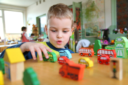 In this photo a young boy plays with blocks that represent toy vehicles.