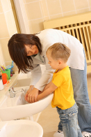 A caregiver helps a child wash his hands.