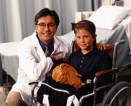 This is a photo of a doctor with a young boy in a wheelchair.